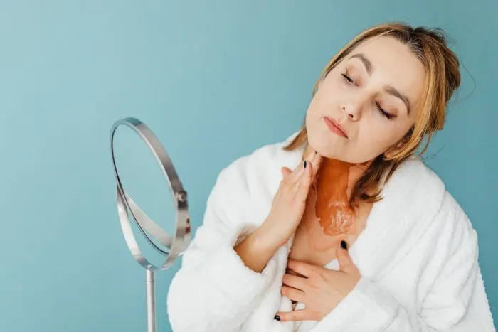 Woman applying a skin cream in front of a mirror