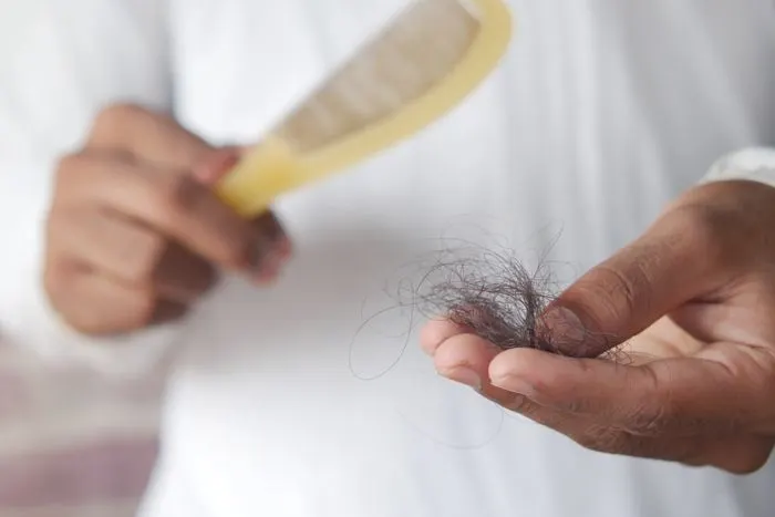 Hand holding a clump of hair that fell out next to a comb