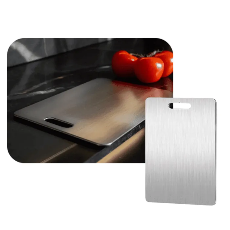 Brushed metal cutting board with a handle cut-out on a dark kitchen bench beside tomatoes
