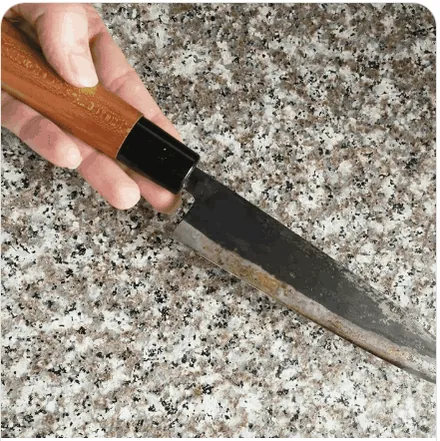 A knife blade resting on a granite bench top
