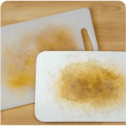 Two plastic chopping boards stained yellow and scarred by knife cuts