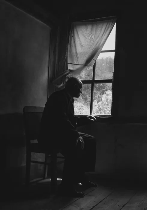 Elderly man sitting alone by a window